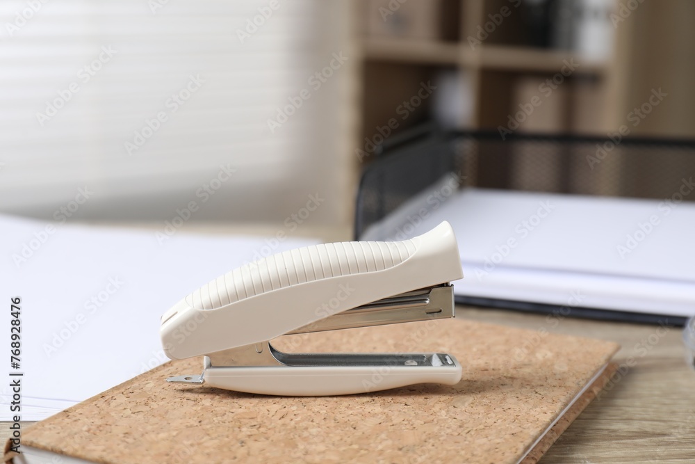 Stapler and notebook on wooden table indoors, closeup Stapler and notebook on wooden table indoors, closeup
