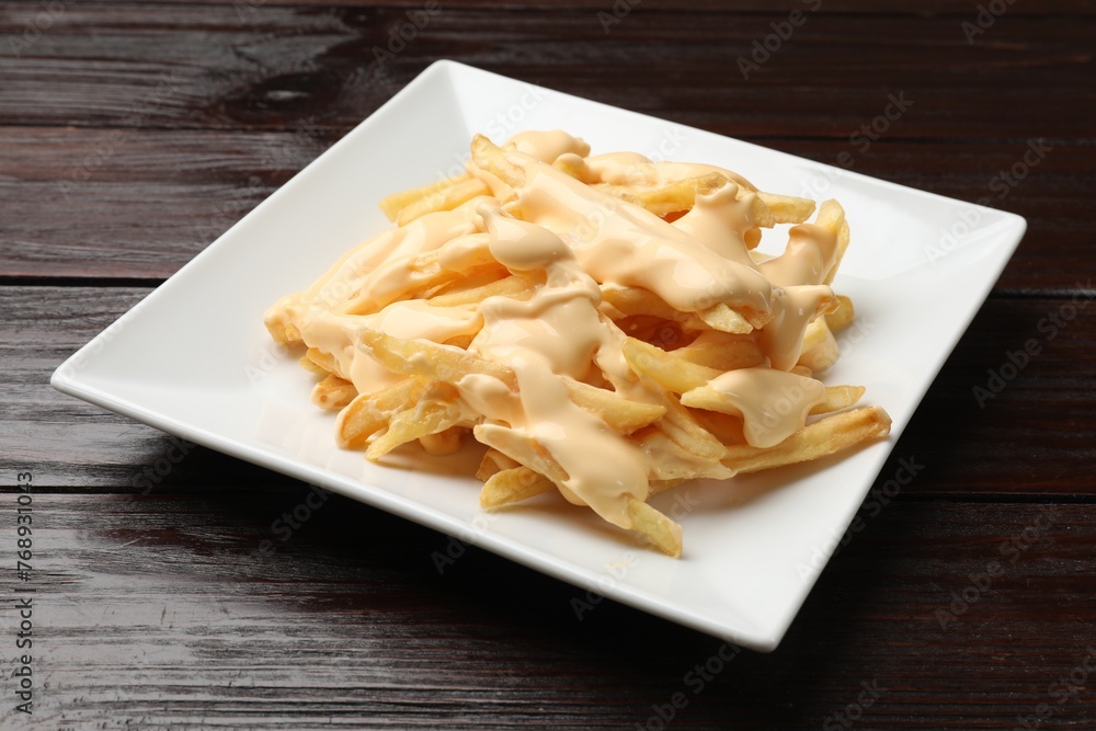 Delicious french fries with cheese sauce on wooden table Delicious french fries with cheese sauce on wooden table