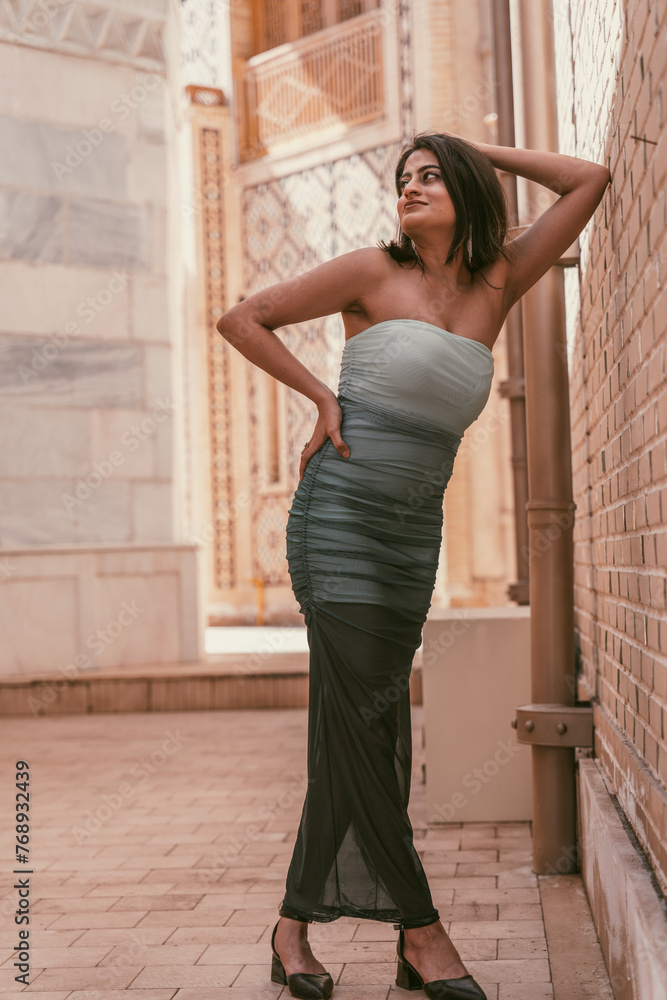 A woman in a dress is posing for a photo in front of a brick wall A woman in a dress is posing for a photo in front of a brick wall