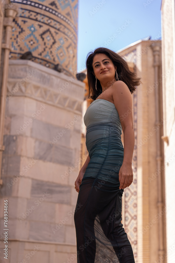 A woman in a blue and black dress stands in front of a building A woman in a blue and black dress stands in front of a building