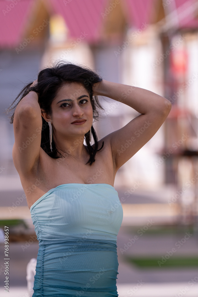 A woman in a blue and white dress is posing for a photo