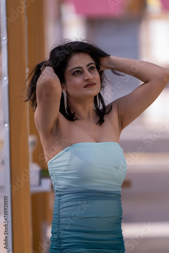 A woman in a blue and white dress is posing for a photo