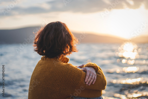 Obraz na płótnie Young mature woman looking at the sunset on the seashore in the rays of the sun w salonie