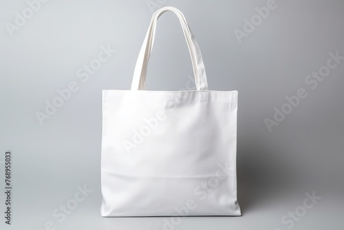 Blank white canvas tote bag on a gray background, perfect for eco-friendly branding and design mockups. © Оксана Олейник