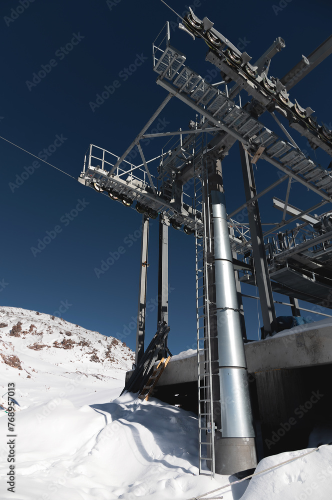 A cable car station high in the mountains under construction. Snowy mountain landscape and construction of a metal structure for a cable car A cable car station high in the mountains under construction. Snowy mountain landscape and construction of a metal structure for a cable car