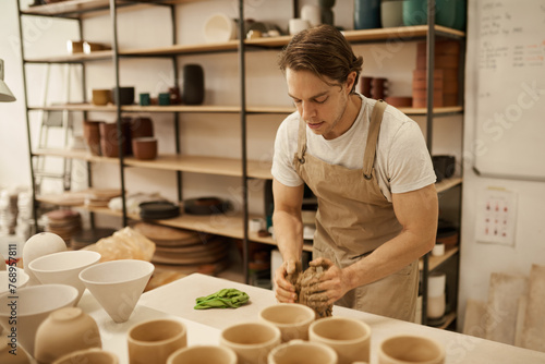 Ceramist shaping clay at a table in a ceramic studio