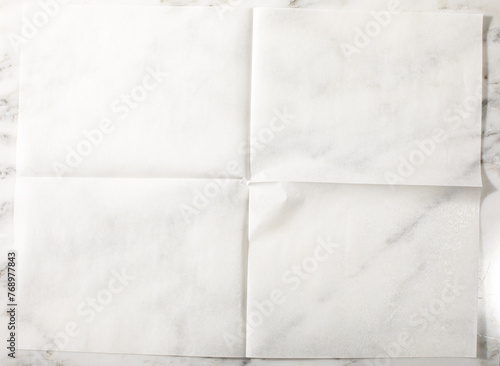 Overhead of folded parchment paper white marble surface photo