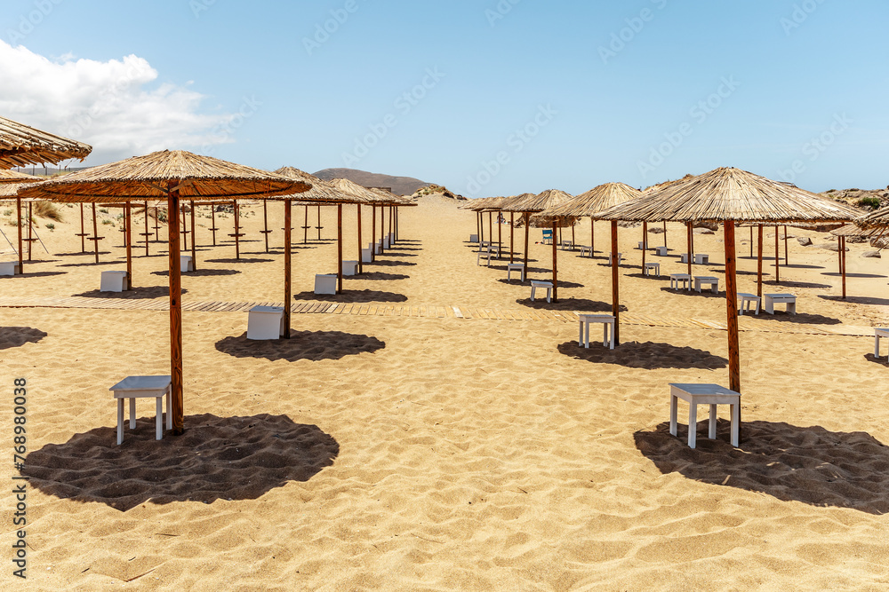 Empty sandy beach with umbrellas in summer with sun light.