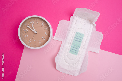 Alarm clock and menstrual sanitary pads. The concept of women's critical days and menstruation. Feminine hygiene. Place for text © Iuliia Pilipeichenko