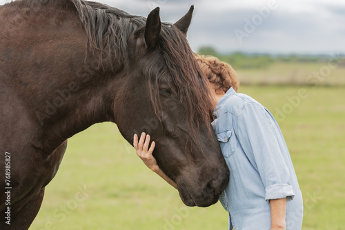 A lady gently holding a Percheron draft horse head in her hand