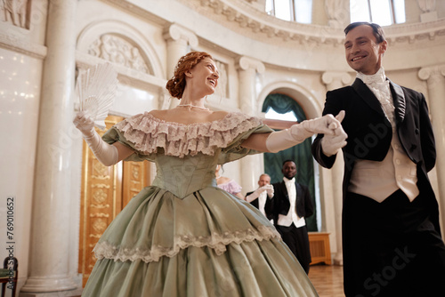 Low angle portrait of beautiful renaissance couple dancing together enjoying ball in palace