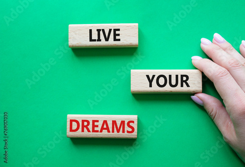 Live your Dreams symbol. Wooden blocks with words Live your Dreams. Beautiful green background. Businessman hand. Business and Live your Dreams concept. Copy space.