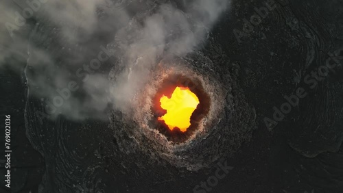 Erta Ale, Danakil Depression, Ethiopia. Top down aerial view of active volcano smoking and lava activity. Cinematic drone footage travelling above the volcanic pit at sunset.  photo