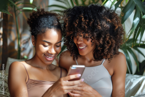 Two beautiful black girlfriends using phone