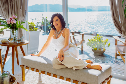 Retrato de uma linda e elegante designer de interiores de mulher madura com cabelos castanhos, sentada em um sofá posando. photo