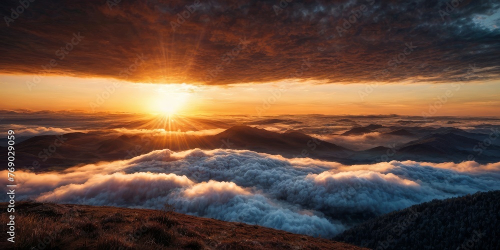   The sun descends behind mountains, casting clouds in the foreground and a backdrop of ranges