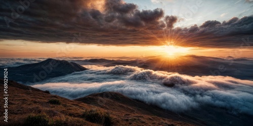  The sun sets behind the clouds atop a mountain, revealing a valley and distant mountains