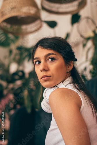 Thoughtful young dark-haired woman in casual clothes wearing headphones,sitting on the couch.Relaxation,meditation,listening music.