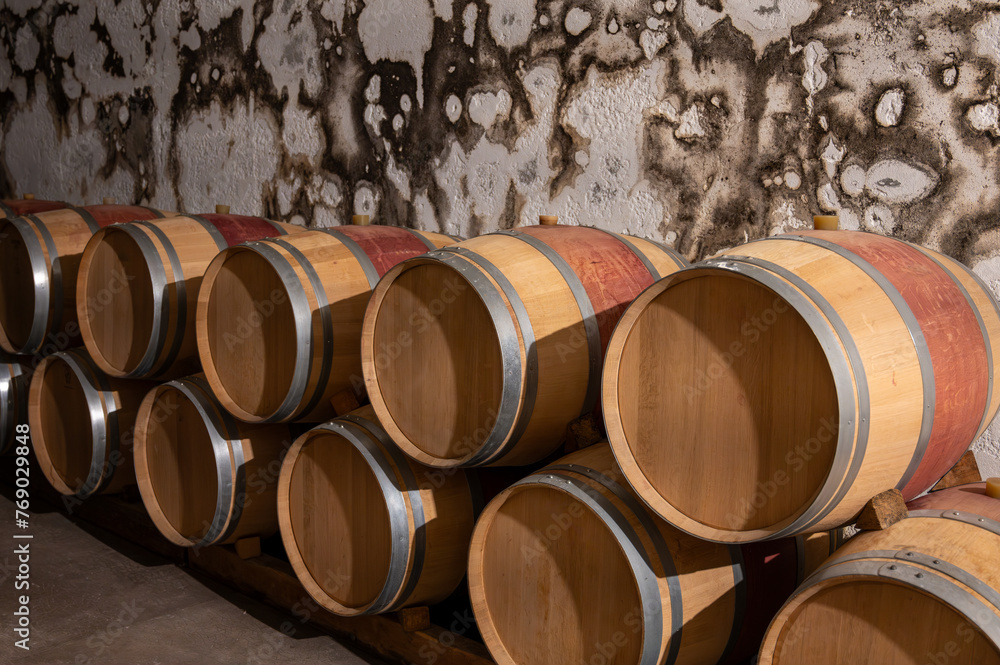 French oak wooden barrels for aging red wine in underground cellar, Saint-Emilion wine making region picking, cru class Merlot or Cabernet Sauvignon red wine grapes, France, Bordeaux French oak wooden barrels for aging red wine in underground cellar, Saint-Emilion wine making region picking, cru class Merlot or Cabernet Sauvignon red wine grapes, France, Bordeaux