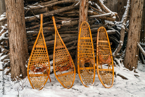 Classic wooden snowshoes, Huron and Bear Paw, against a pile of firewood