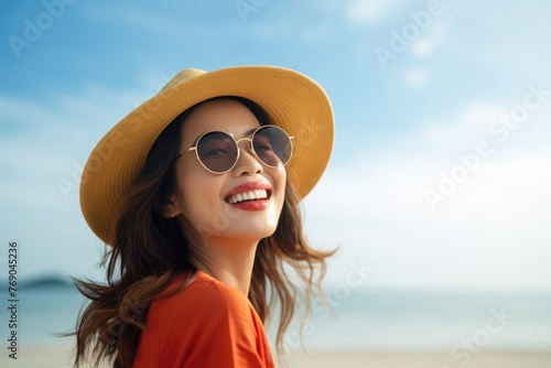 Beautiful Happy young Asian tourist woman wearing a beach hat, and sunglasses, going to travel on holiday on a blue sky background. travel concept.