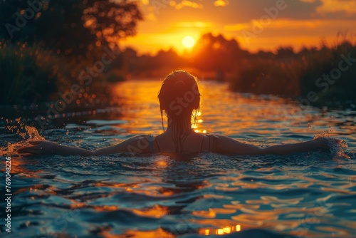 An evocative image of a person soaking in the tranquil beauty of a sunset over water photo