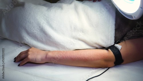 a master performs an electrodepilation procedure on a girl's arm  photo