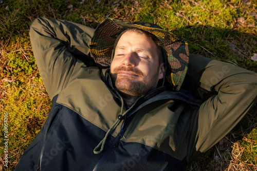 peaceful satisfied man sleeping and resting on green forest moss. nature escape and tranquility. stress relief and mental health