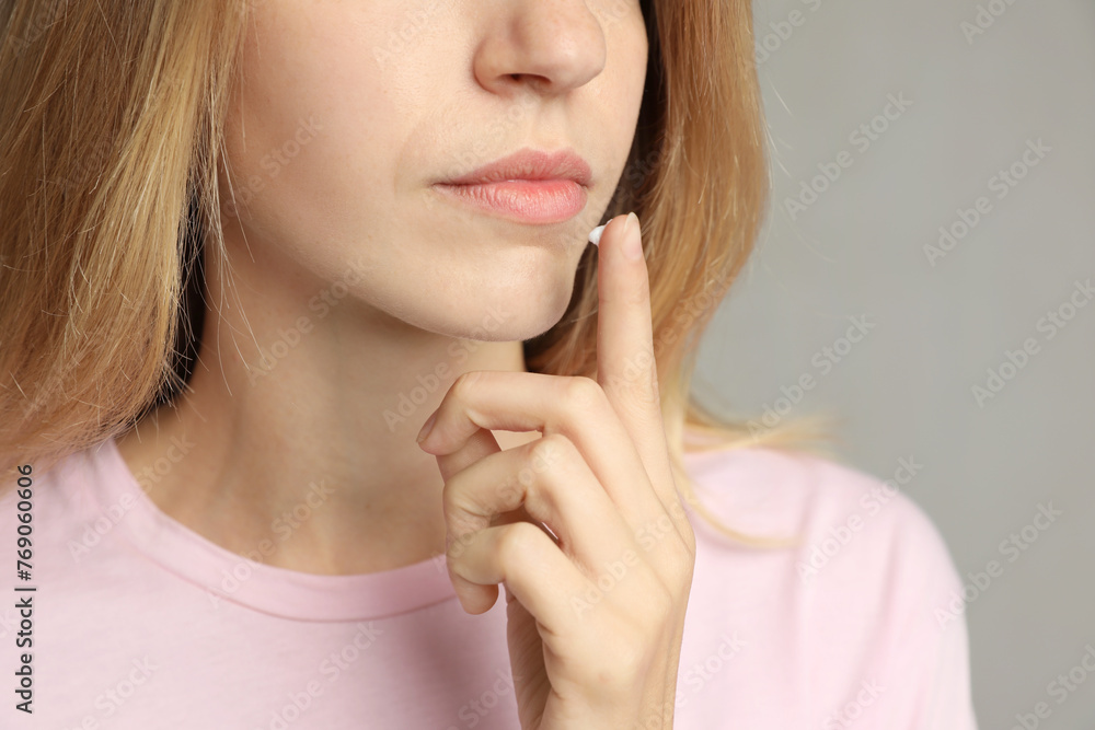 Woman with herpes applying cream onto lip against light grey background, closeup Woman with herpes applying cream onto lip against light grey background, closeup