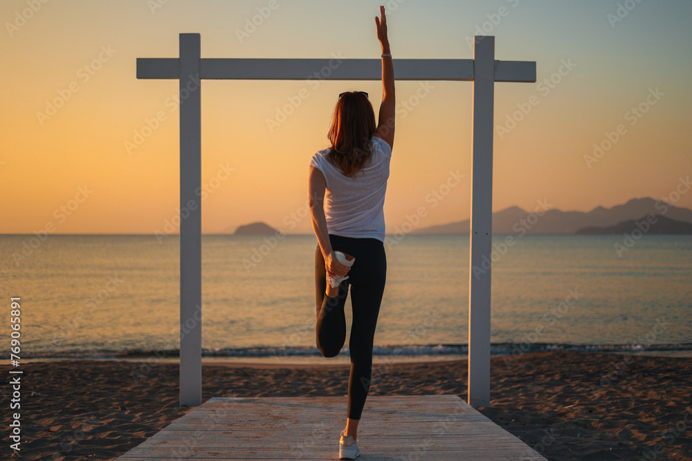 Joga, młoda dziewczyna praktykuje asany na wakacjach nad morzem. Wschód słońca na greckiej wyspie Kos. Ćwiczenia rozciągające, sport na powietrzu.  - obrazy, fototapety, plakaty 