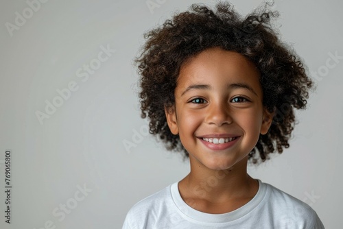 A young child with curly hair is smiling and looking at the camera © top images