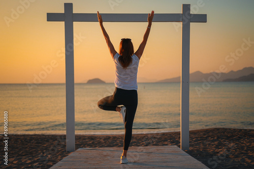 Joga, młoda dziewczyna praktykuje asany na wakacjach nad morzem. Wschód słońca na greckiej wyspie Kos. Ćwiczenia rozciągające, sport na powietrzu. 