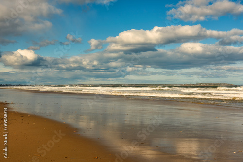 ocean coast on a sunny day with fluffy clouds. Reflection of the sky in the water on the shore. Atlantic coast of the USA
