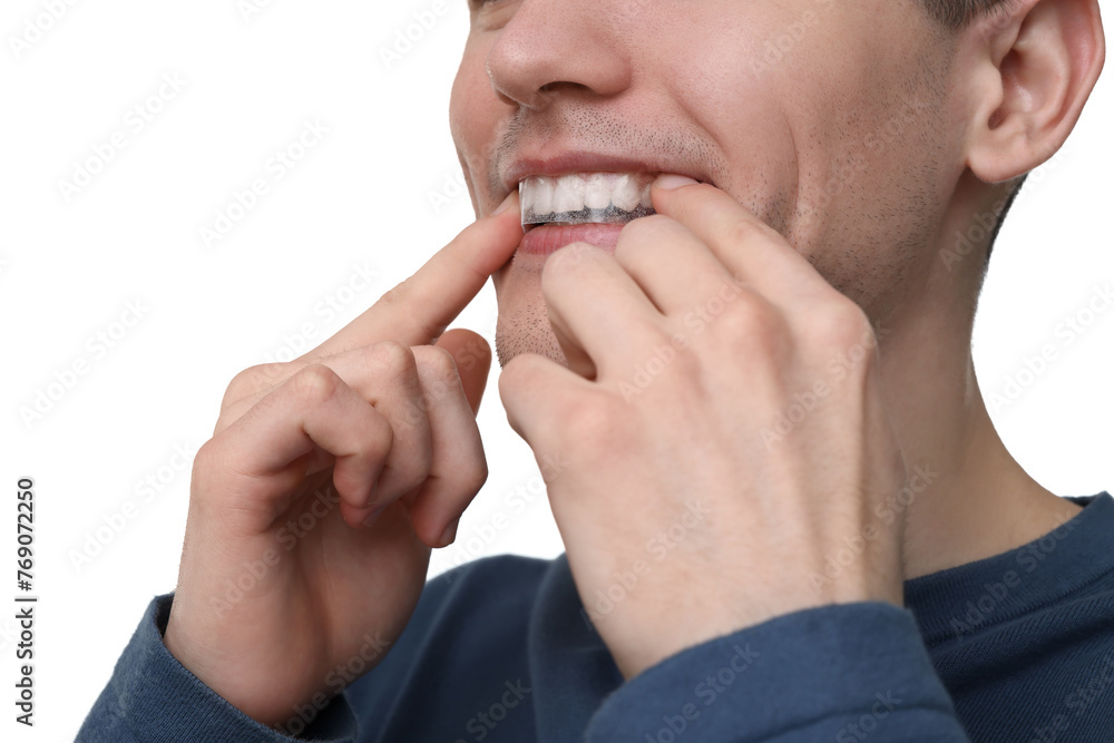 Young man applying whitening strip on his teeth against light background, closeup Young man applying whitening strip on his teeth against light background, closeup