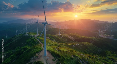 Wind turbines on mountain slope at sunset viewed from above
