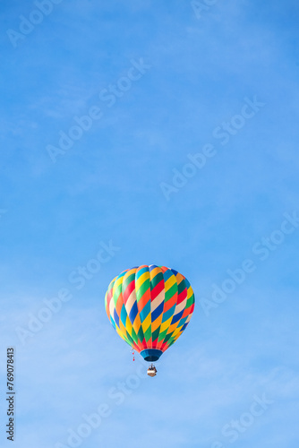 Colorful hot air balloon flying across the blue sky