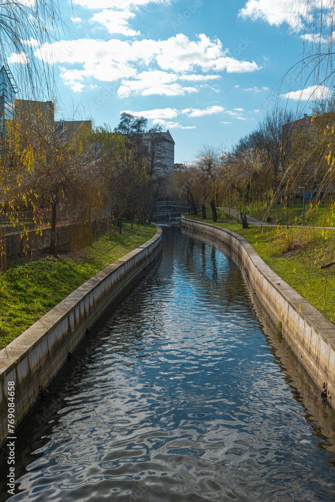 Detail of Pavia River in Viseu, Portugal, with water, green trees and a blue sky with clouds