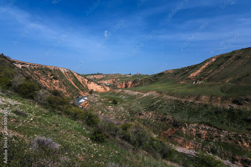 Landscape with canyon and Aksu river in Kazakhstan in spring under blue sky