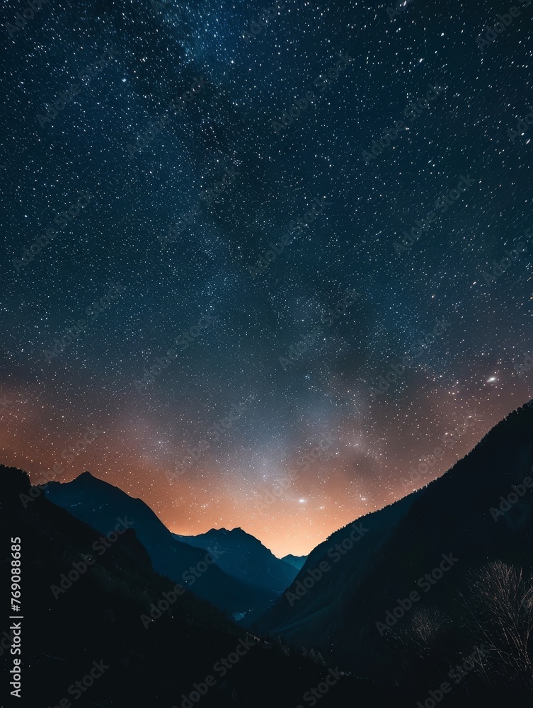 A tranquil nightscape featuring a dazzling star-studded sky transitioning to a warm twilight hue above the soft silhouettes of mountain ranges..