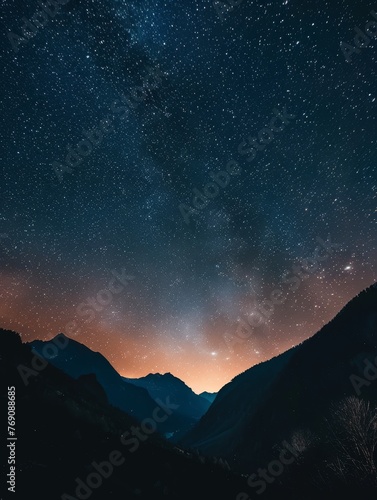 A tranquil nightscape featuring a dazzling star-studded sky transitioning to a warm twilight hue above the soft silhouettes of mountain ranges.. © Valentyna