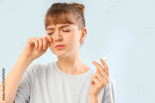 Young woman with eye drops ...