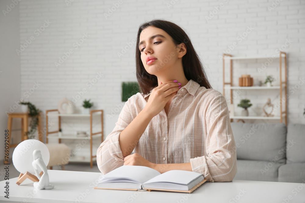 Young woman with book suffering from thyroid gland problem at home Young woman with book suffering from thyroid gland problem at home