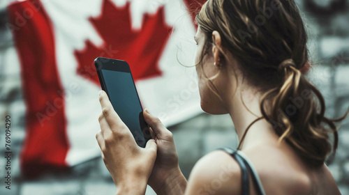 Woman with mobile phone with Canadian flag on the background on the street