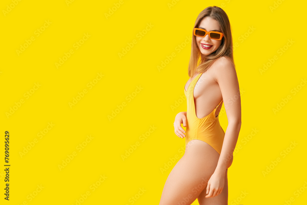 Pretty young woman in tank swimsuit on yellow background - obrazy, fototapety, plakaty 