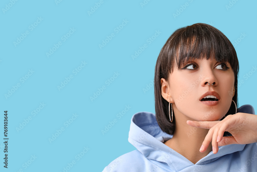 Stylish young woman with nose piercing on blue background Stylish young woman with nose piercing on blue background
