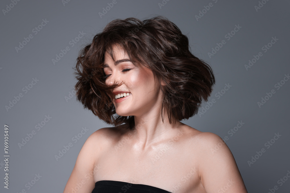 Portrait of beautiful young woman with wavy hairstyle on grey background Portrait of beautiful young woman with wavy hairstyle on grey background
