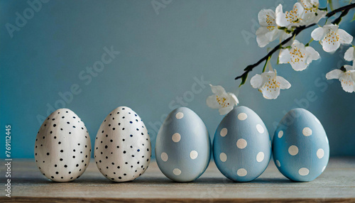 Um conjunto de ovos pintados de bolinhas, nas cores azul e branco e um galho de flores brancas decorando. Espaço para escrever. photo
