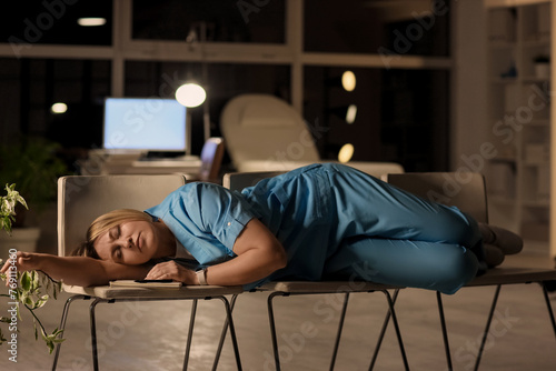 Female nurse sleeping on chairs at hospital in evening photo