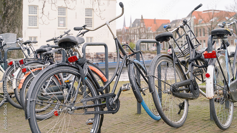 Delft, Netherlands. Bicycles parked alongside a channel on beautiful old buildings background.