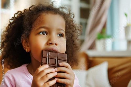 Adorable black kid nibbles chocolate bar